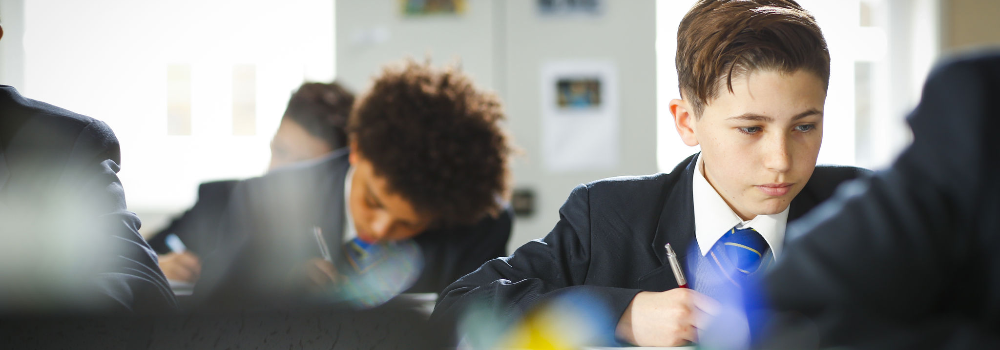 Students making notes during a lesson in a classroom.