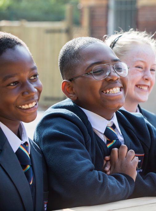 Students sitting on a bench outside smiling ear to ear