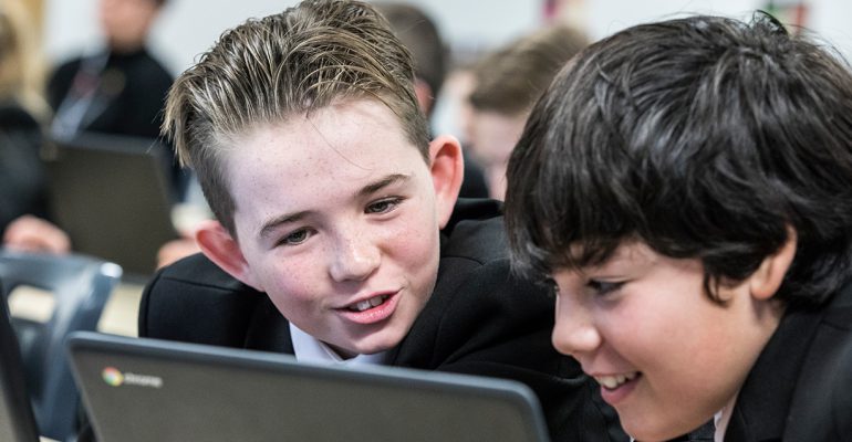 Two students using a chromebook in a classroom