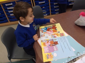 A young boy reading through a story book in a classroom