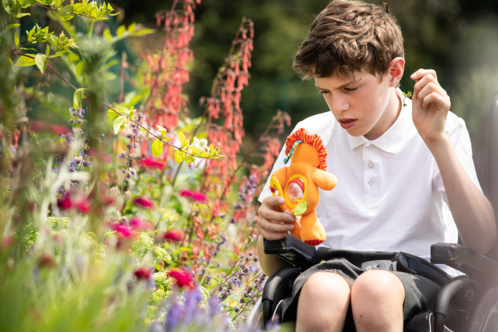 A young student in a wheelchair admiring the flowers