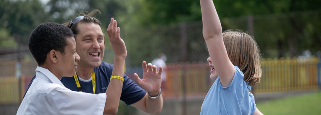 Two students and a teacher all cheering with their fists in the air