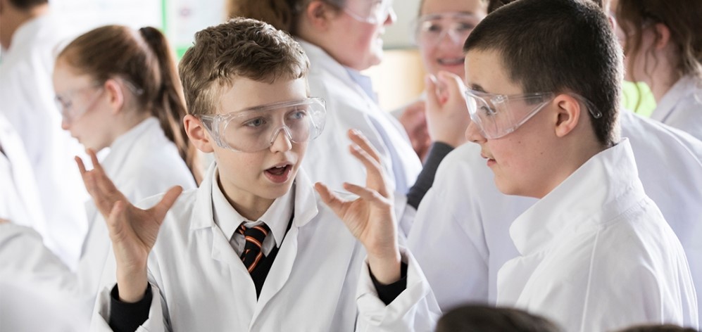 Students wearing safety goggles and lab coats during science lesson