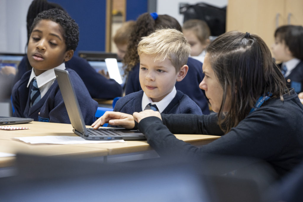 A young student is working with his teacher on the computer during his lesson.