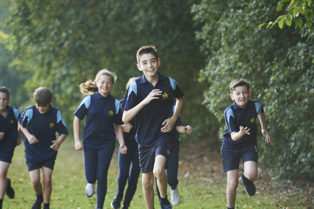 A group of students running towards to the camera while smiling and laughing
