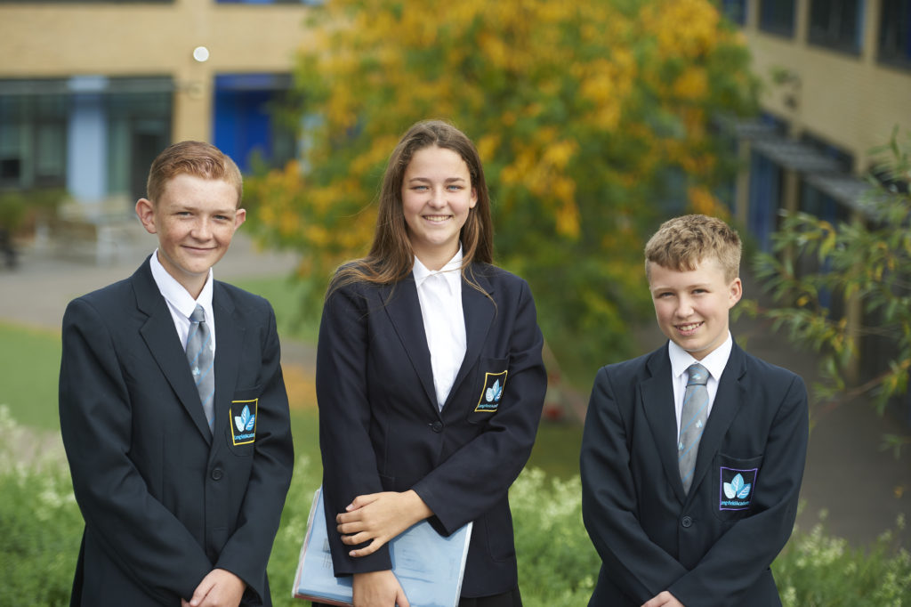 Two boys and One female student wearing the school uniform smiling at the camera