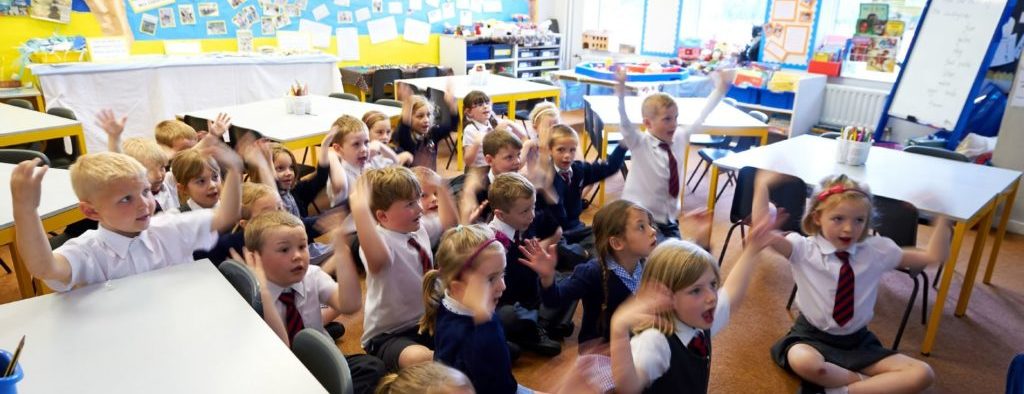 A group of children sat on the carpet of a classroom