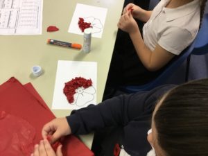 Two children making tissue paper poppy art