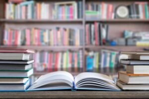 Books and textbook on wooden desk in library selective focus , Piles of books on reading desk in school with copy space for text.World book day and education concept.