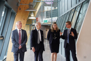 Lord Leigh of Hurley is pictured walking down a corridor at The Leigh Academy during a recent visit there. He is accompanied by members of the LAT Executive Team.