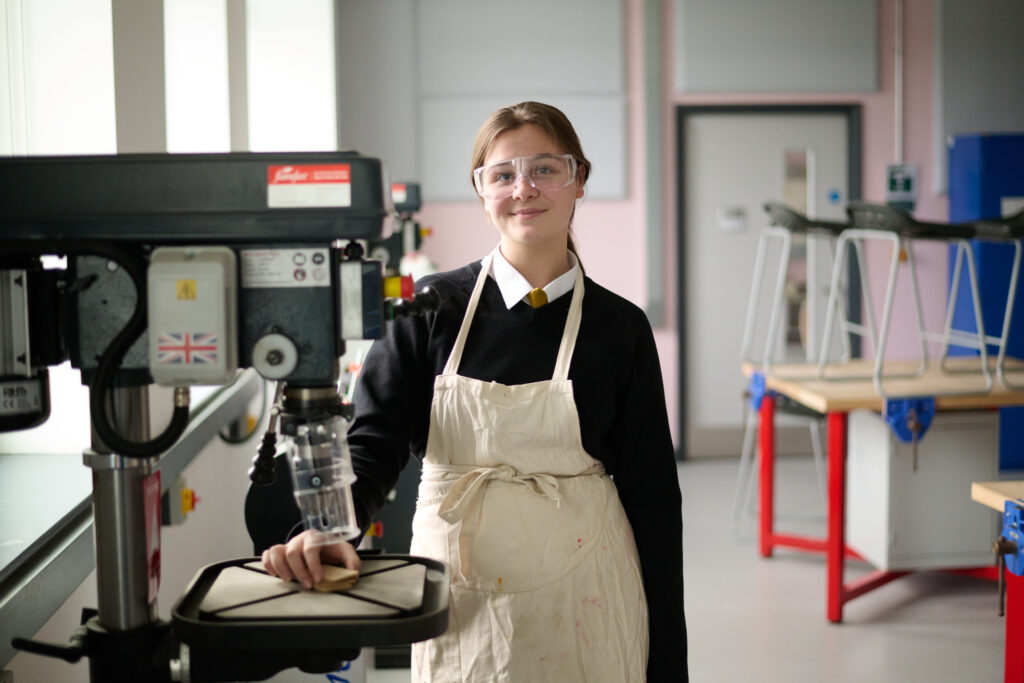 Female student stood next to a machine in a workshop